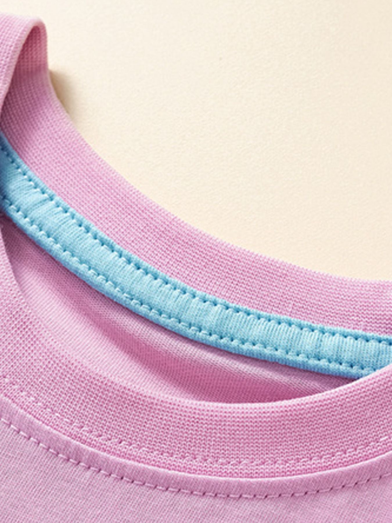 Close-up detail of the pink crew neckline with light blue inner trim on children's T-shirt