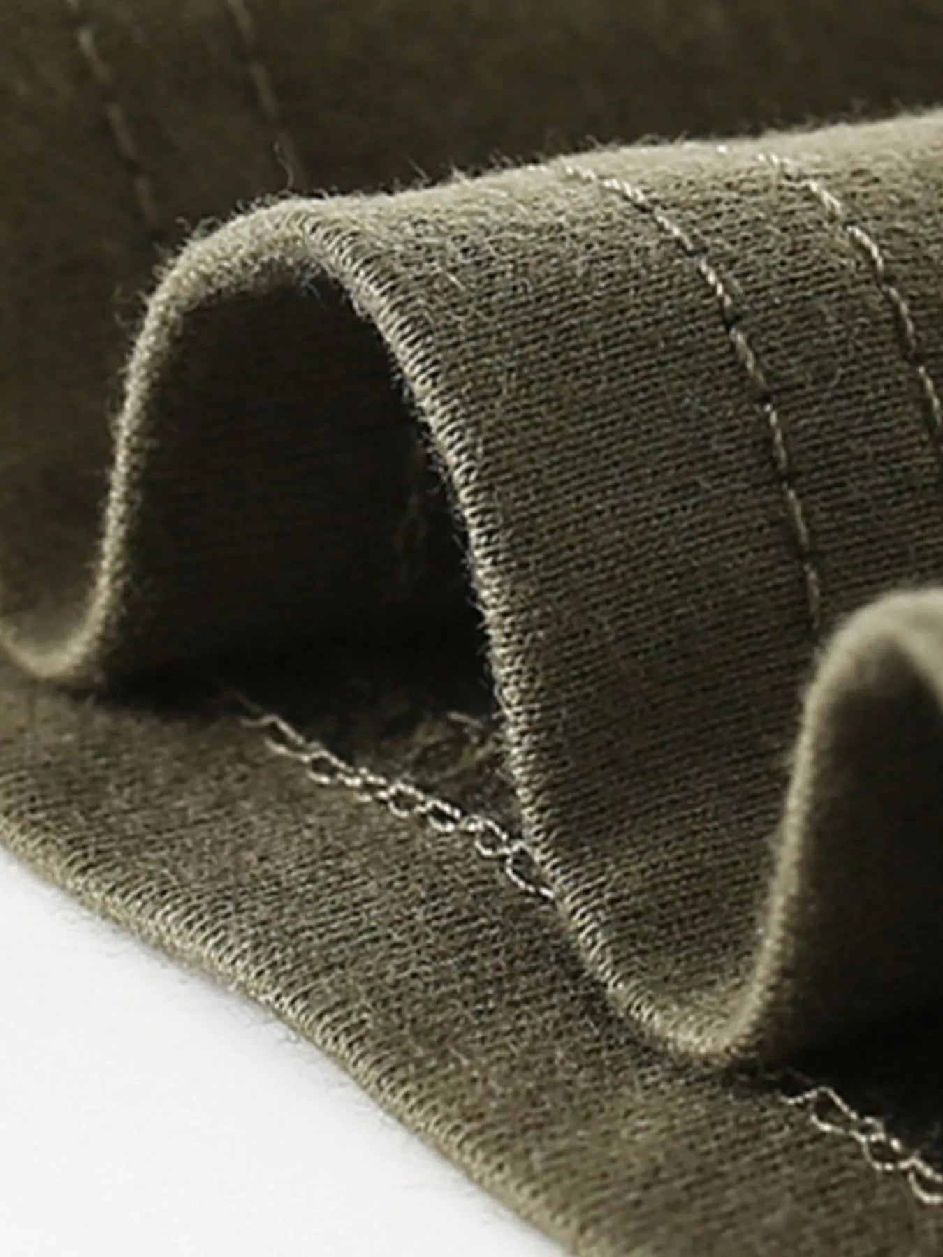 Close-up of the army green shirt hem showing neat stitching and soft folded fabric
