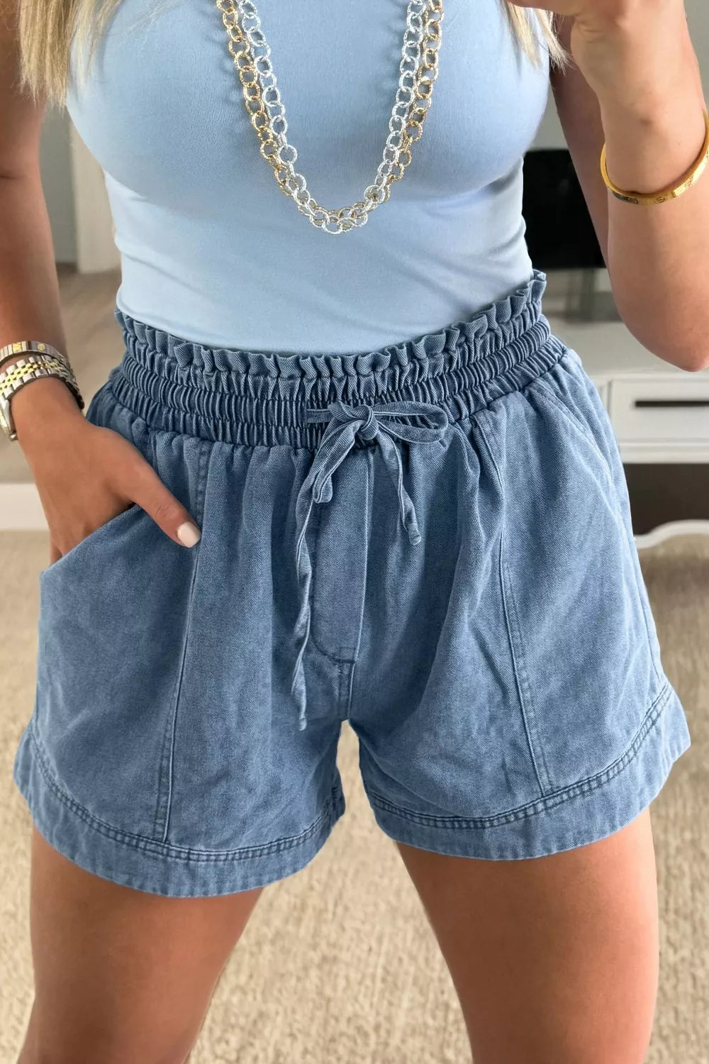 Women's denim shorts with a smocked elastic waist, drawstring, and pockets.