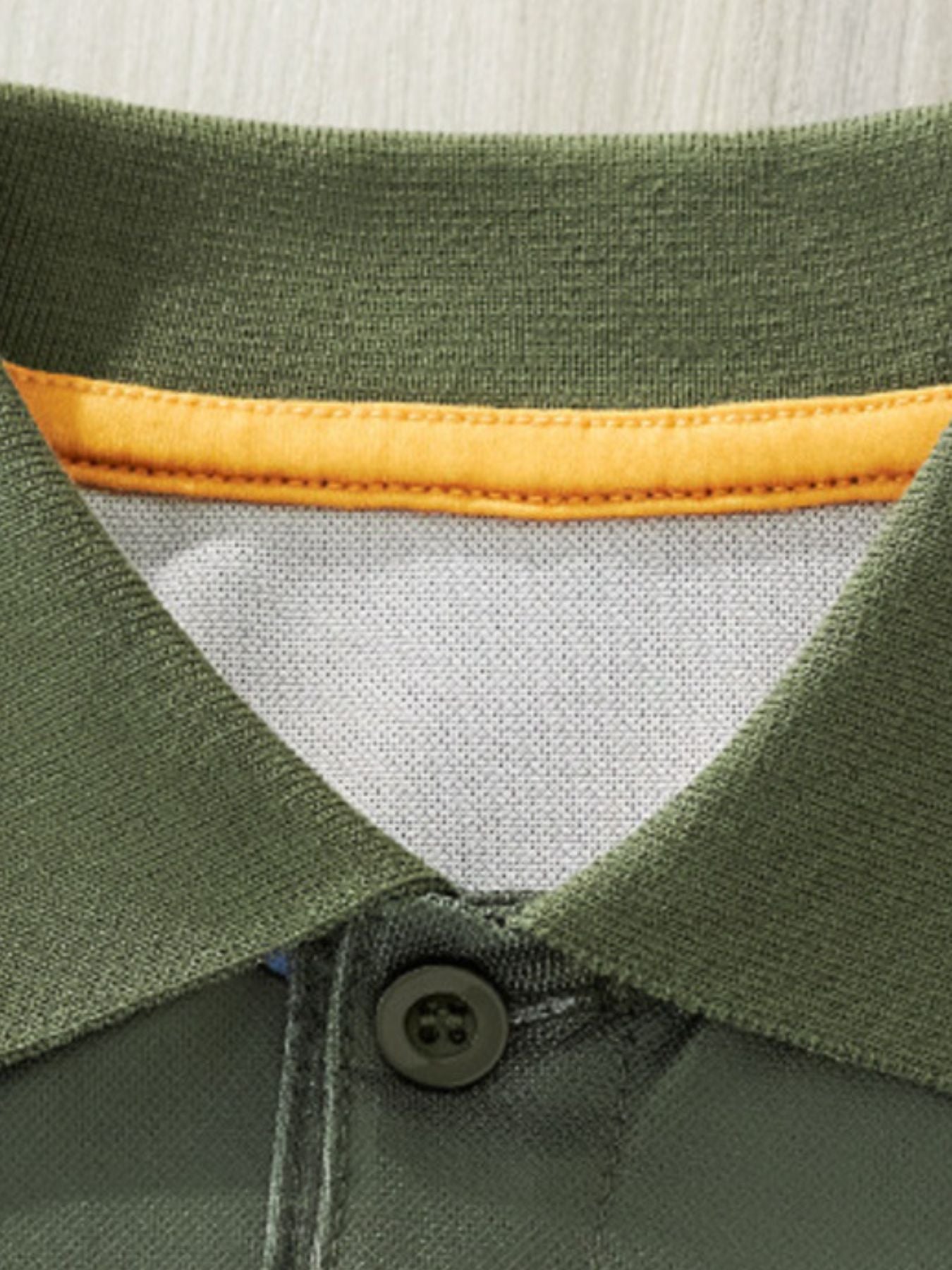 Close-up detail of the army green polo collar with yellow inner trim and button