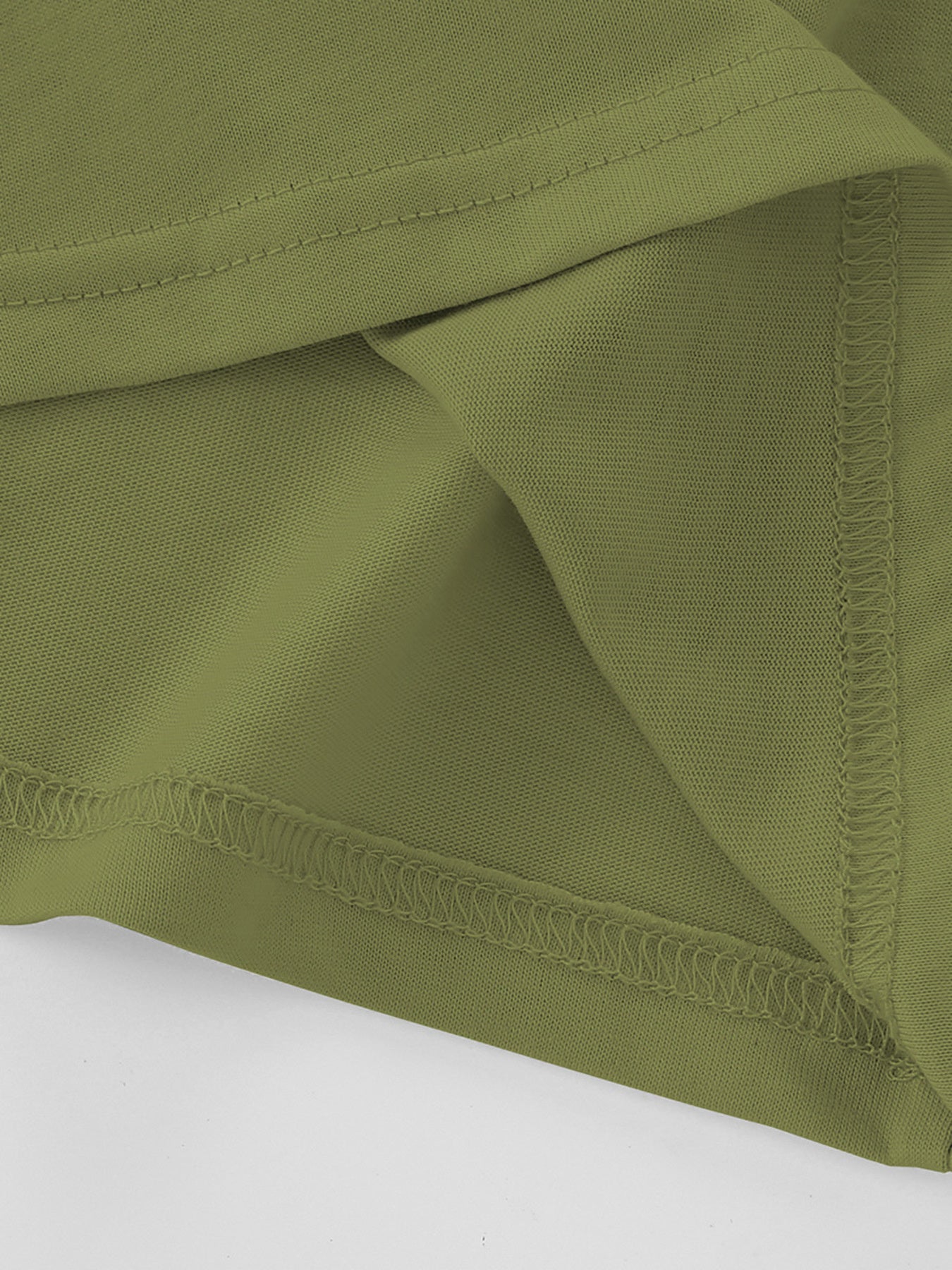 Close view of the moss green children's tee hem and side seam showing fine overlock stitching