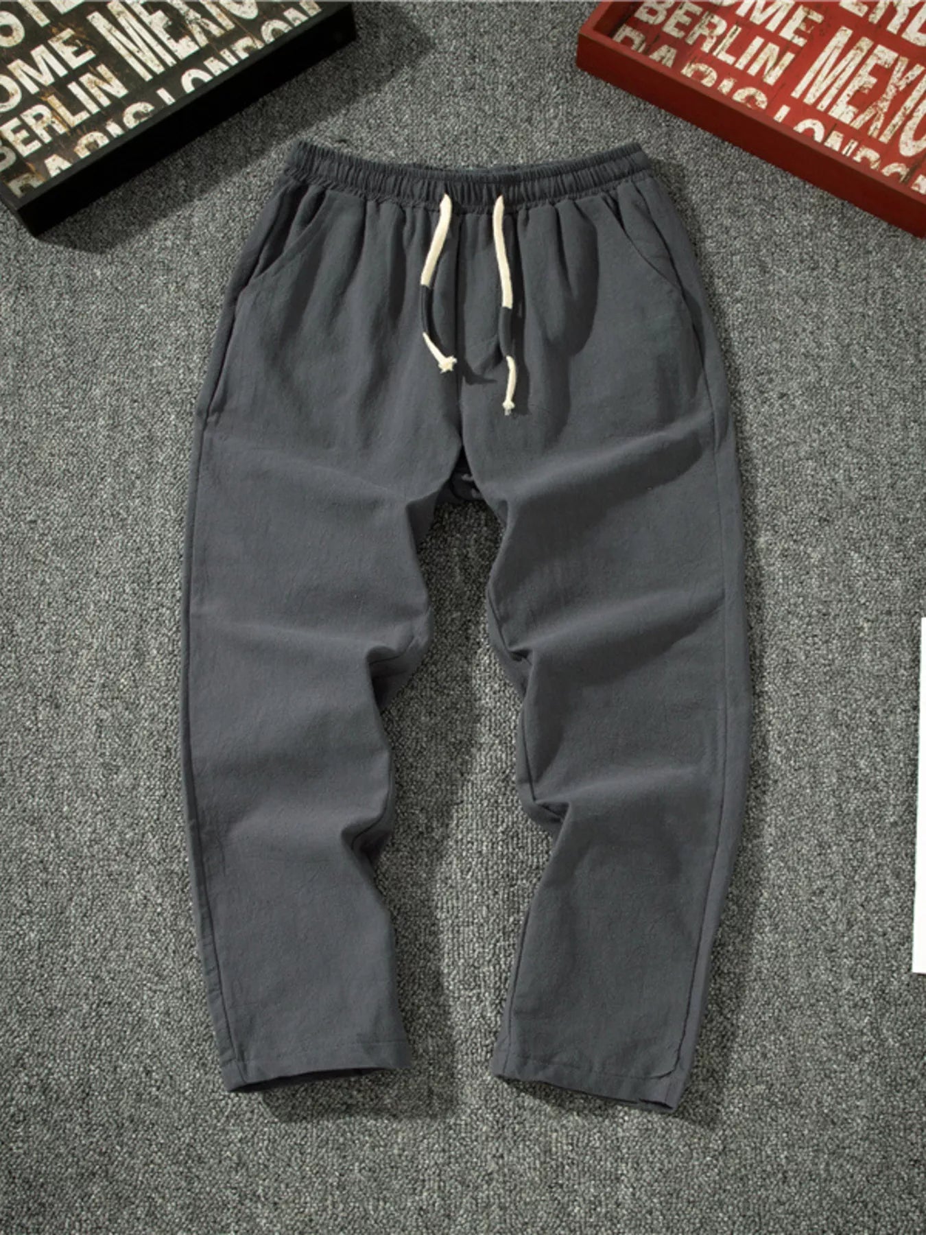 Men's dark gray loose-fit pants with a drawstring waist and pockets.