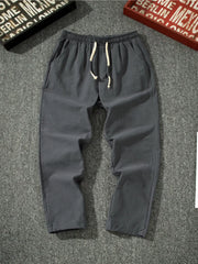 Men's dark gray loose-fit pants with a drawstring waist and pockets.