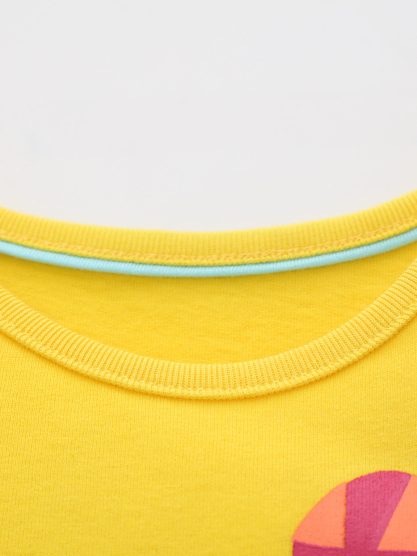 Close-up of yellow children's t-shirt neckline with light blue inner trim