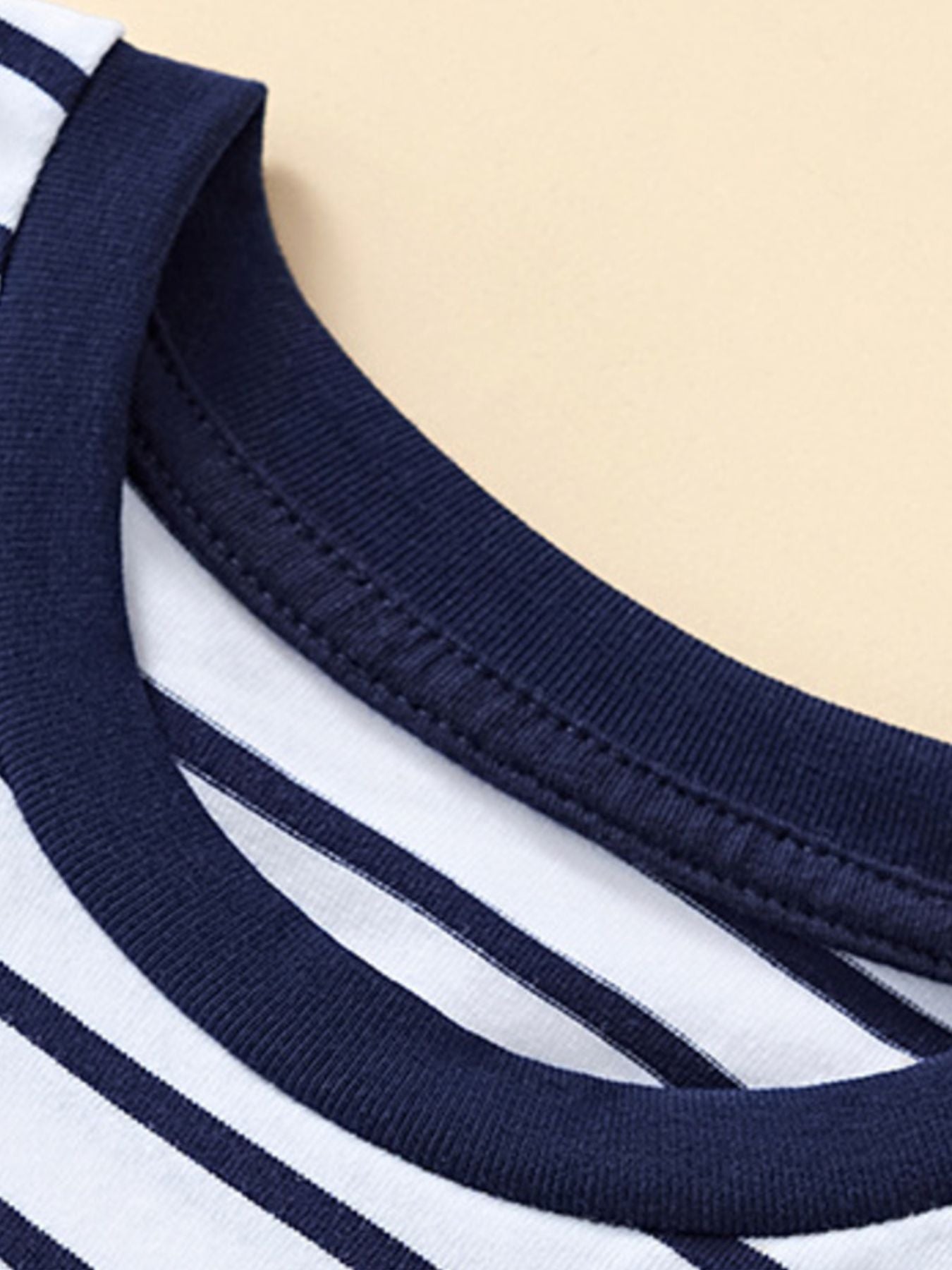 Close-up of the navy ribbed crew neckline and stitching on a striped children's T-shirt