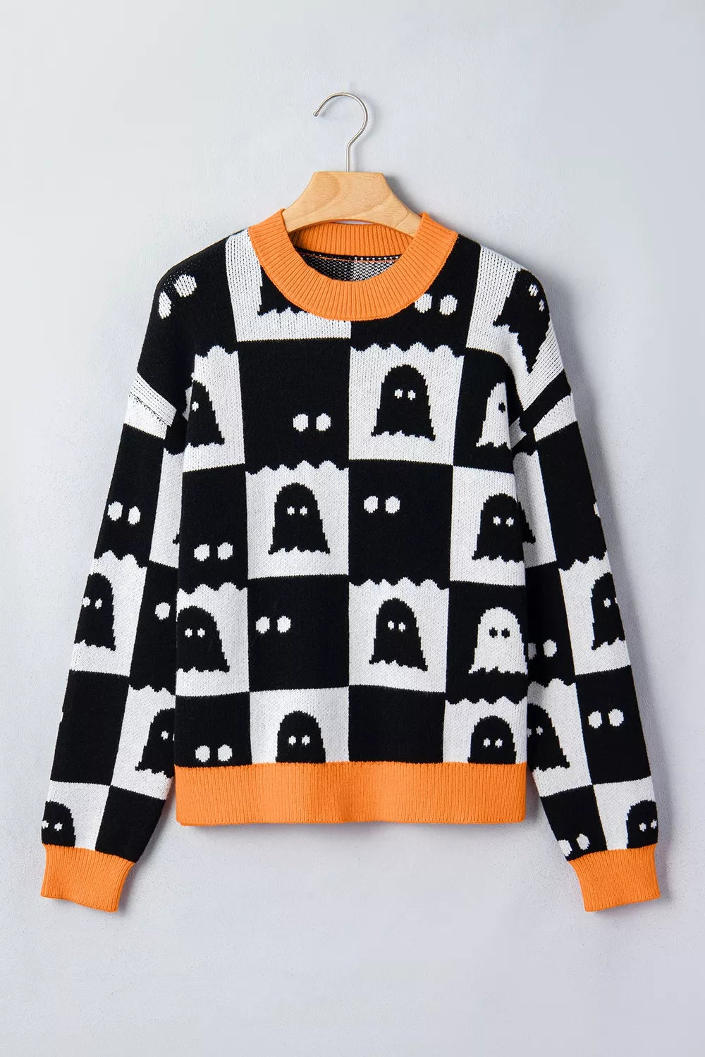 Flat front view on a hanger of a checkerboard ghost sweater with orange trim