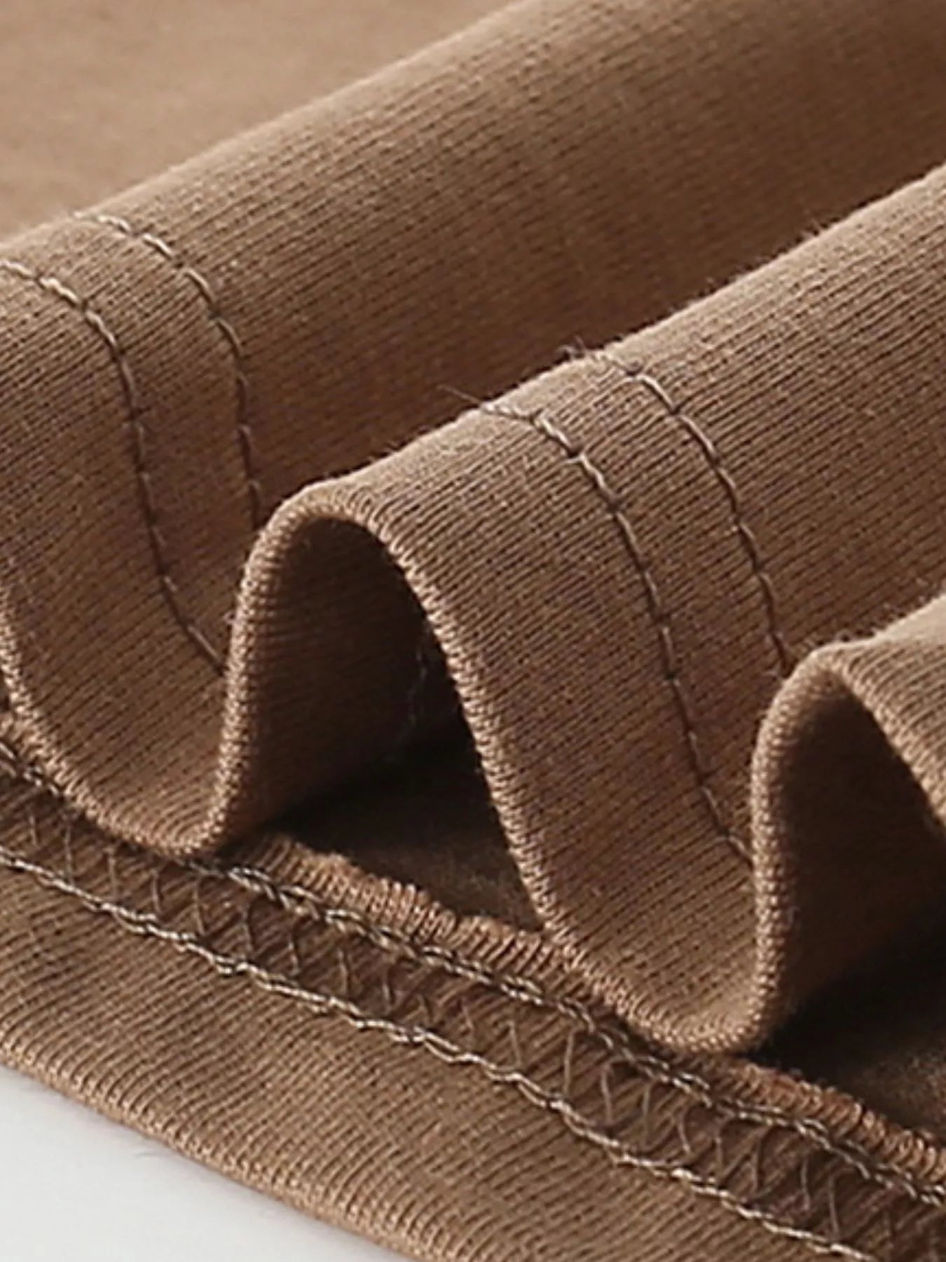 Close-up of caramel children's t-shirt folded hem stitching and knit fabric detail