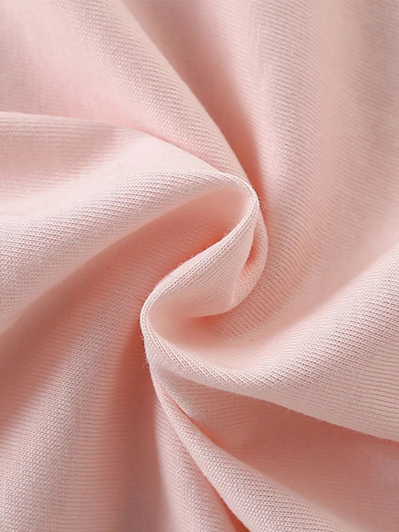 Close-up of soft blush pink cotton fabric texture with gentle folds