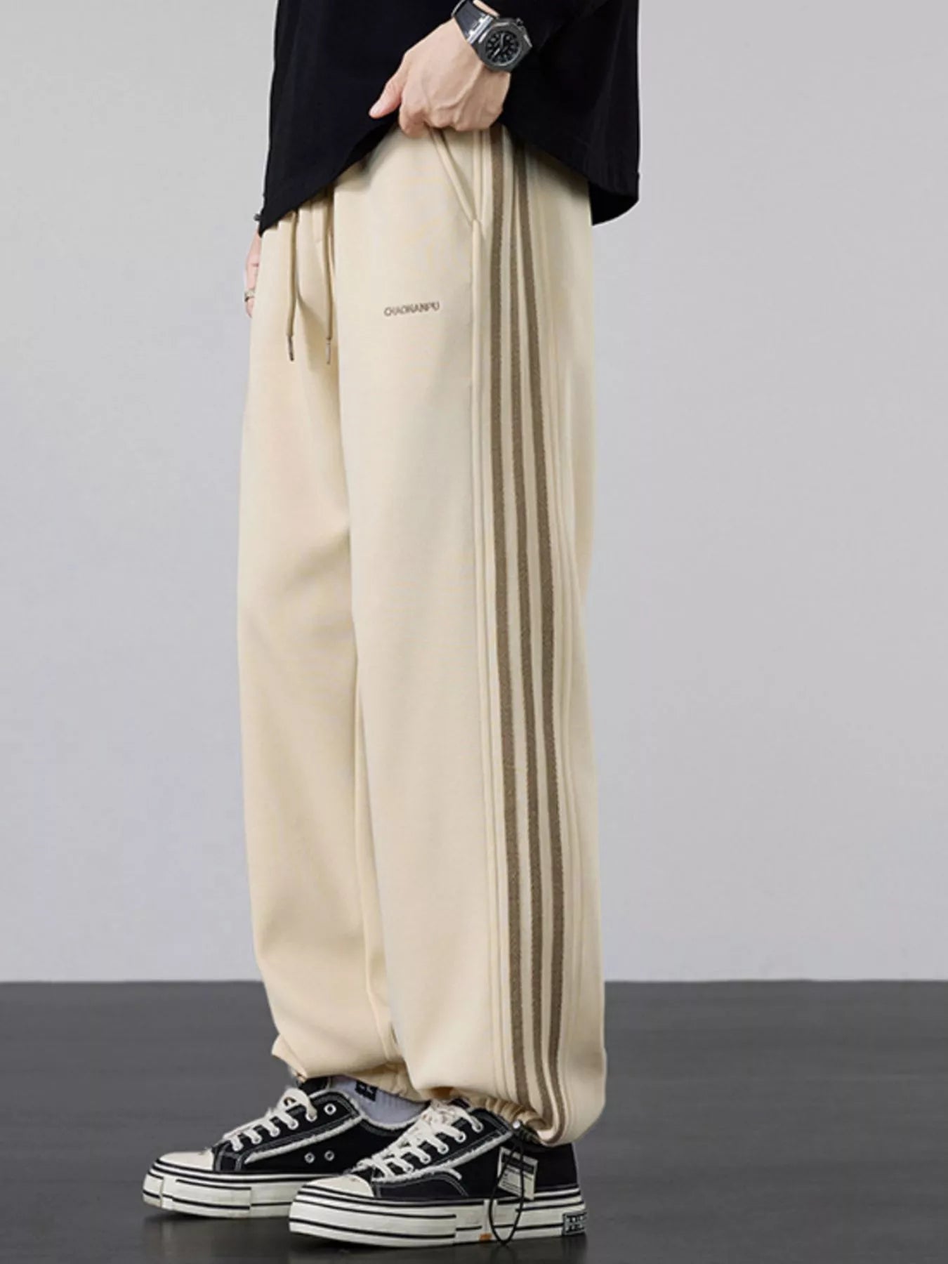Men's khaki striped wide-leg sweatpants with a drawstring waist and pockets.
