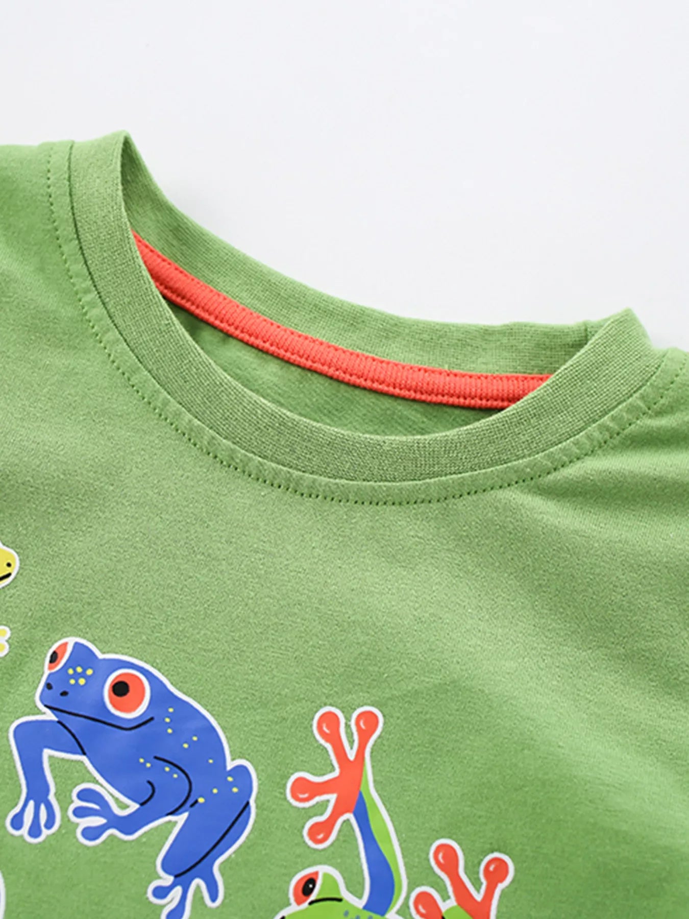 Close-up of lime children's t-shirt neckline with orange inner trim and frog print edge