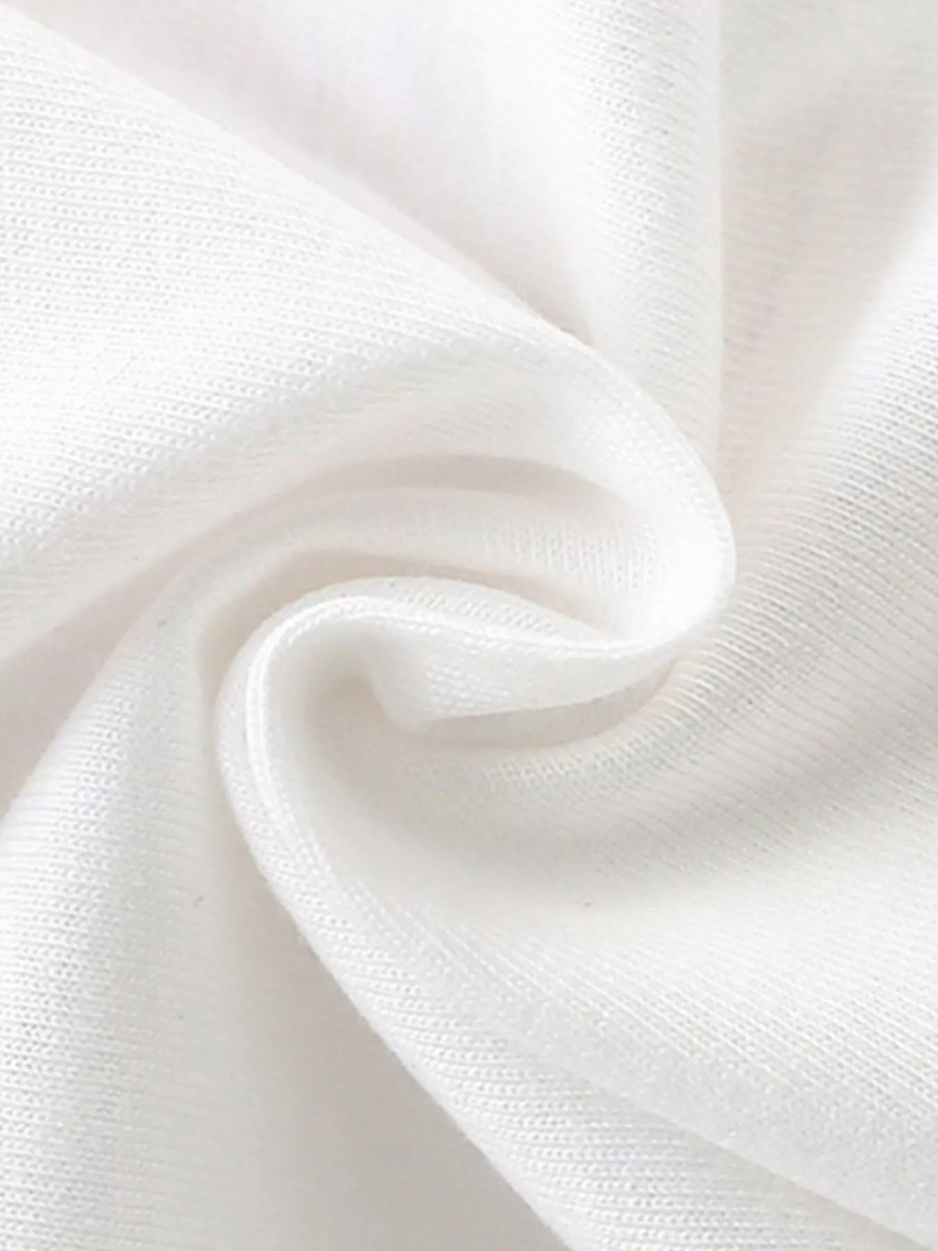 Close-up of soft folded white knit fabric texture of children's short sleeve t-shirt