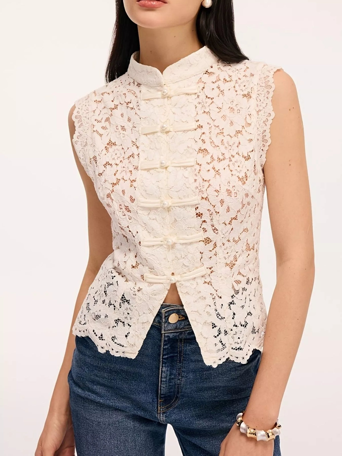 Front view of white lace sleeveless top with knot buttons and mandarin collar on model