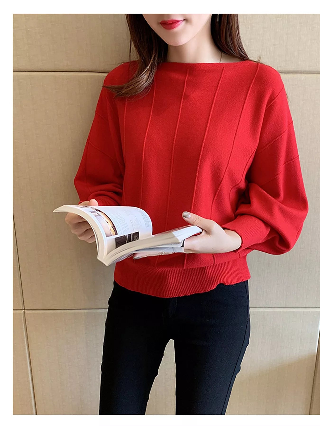 Front view of the red batwing sleeve knit top with vertical seams, holding an open book.
