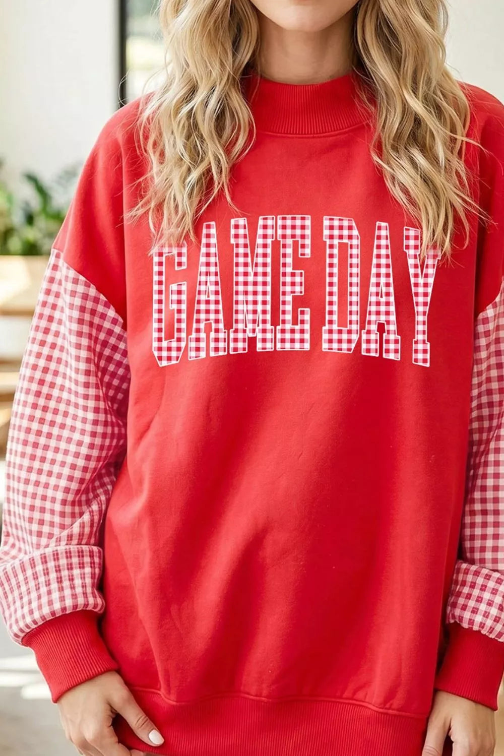Straight front view of red mock neck sweatshirt with plaid sleeves and GAME DAY lettering