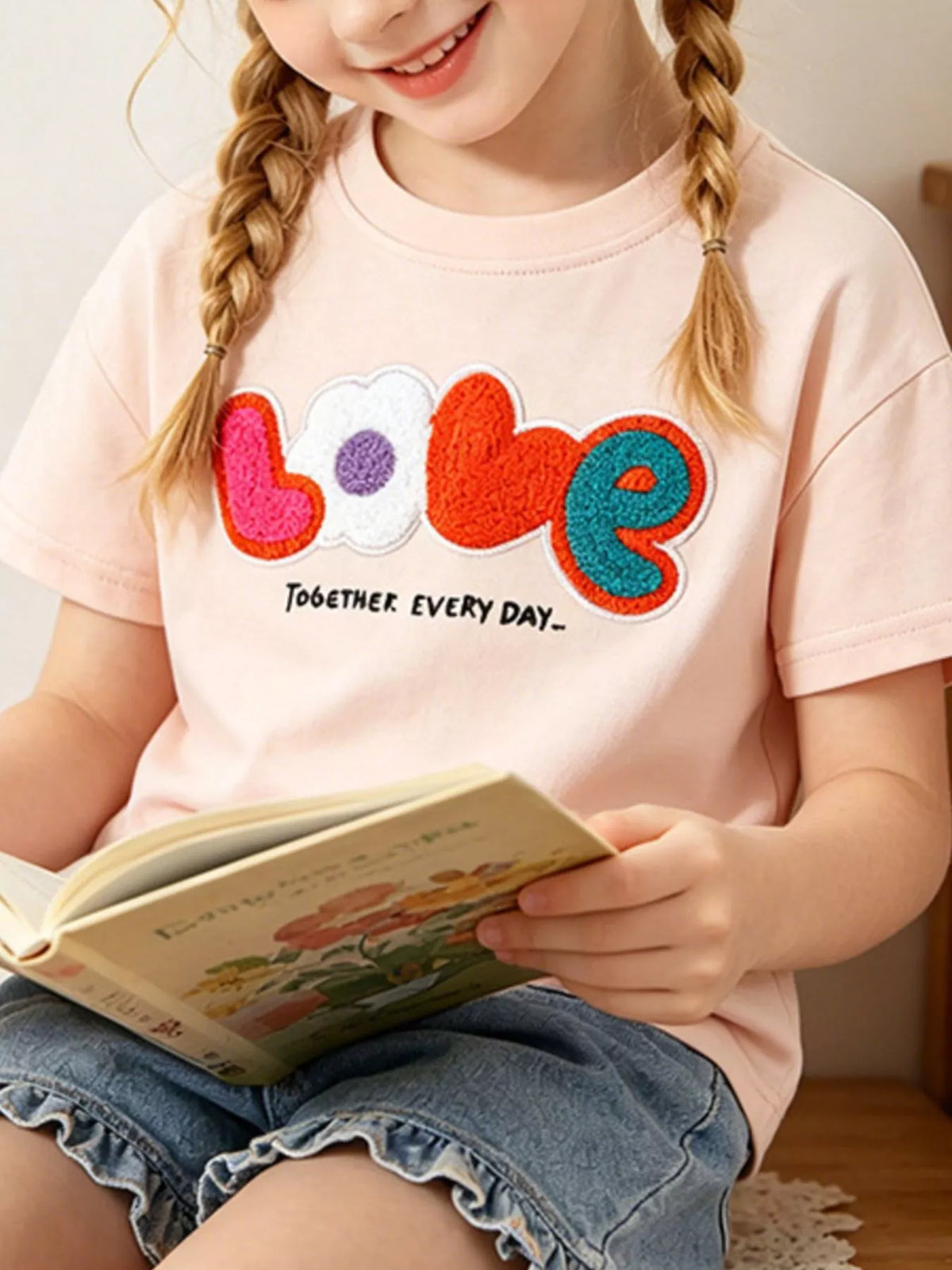 Watermelon pink children's round neck t-shirt with colorful textured LOVE lettering and heart and flower shapes