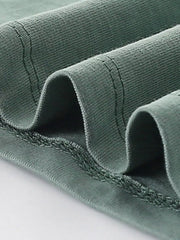 Close-up of the sage shirt hem showing double stitching and soft folded fabric