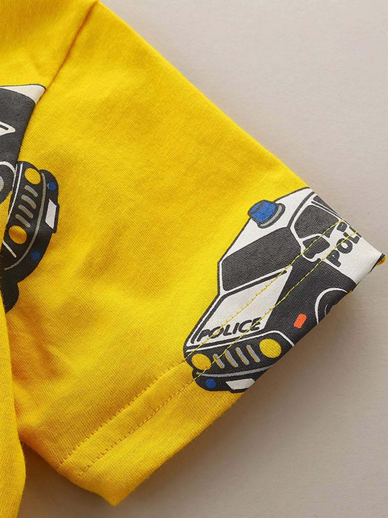 Close up of yellow children's t-shirt sleeve hem stitching with police car print detail