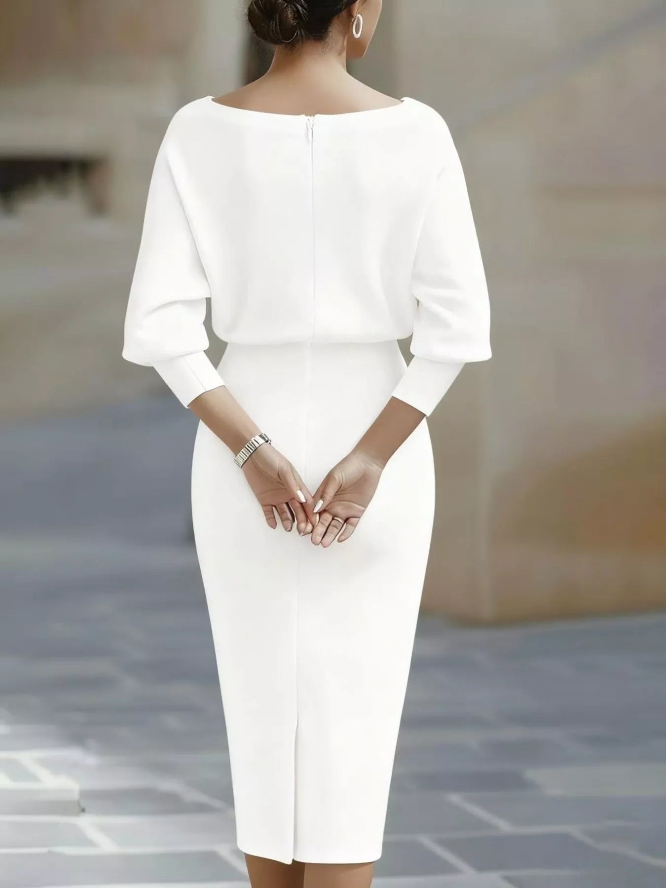 Back view of a white cowl neck bodycon midi dress showing a back zip outdoors