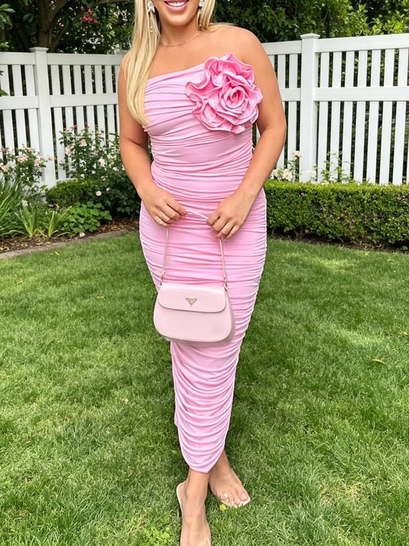 Pink ruched tube bodycon midi dress with large flower detail, front view outdoors