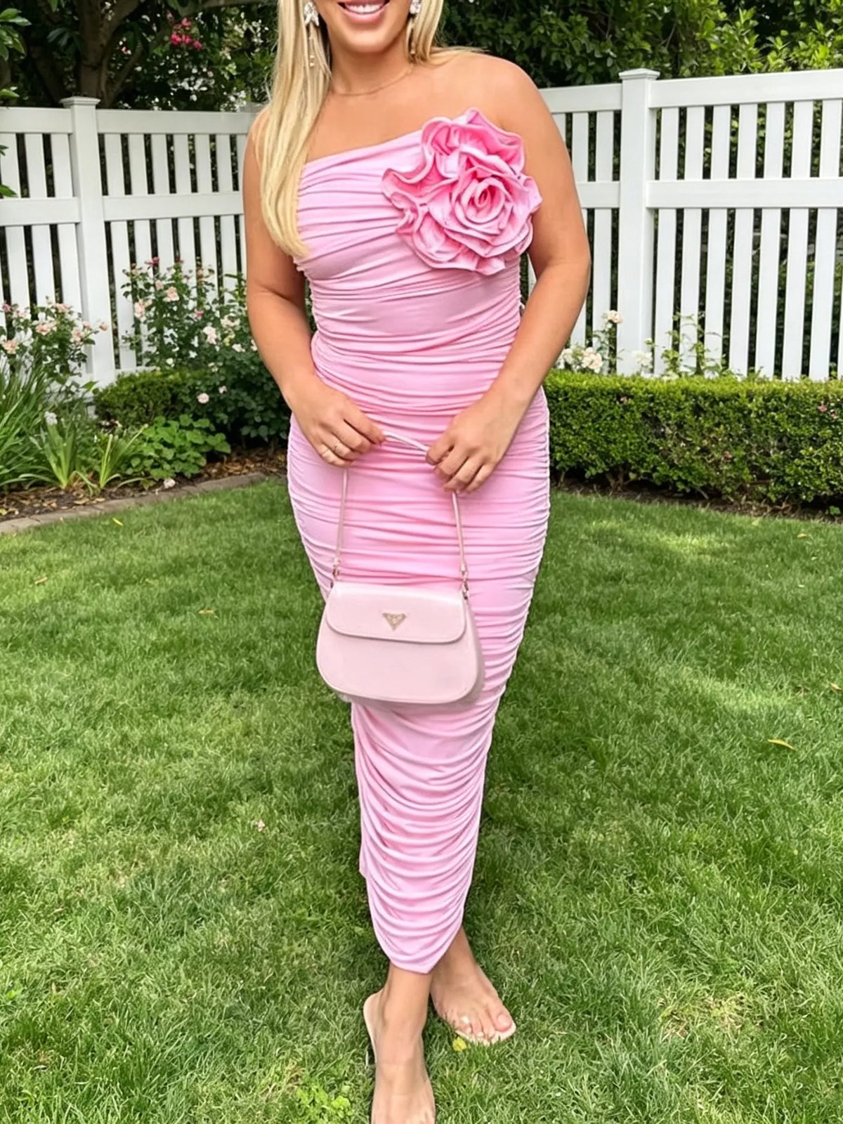 Pink ruched tube bodycon midi dress with large flower detail, front view outdoors