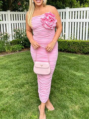 Pink ruched tube bodycon midi dress with large flower detail, front view outdoors