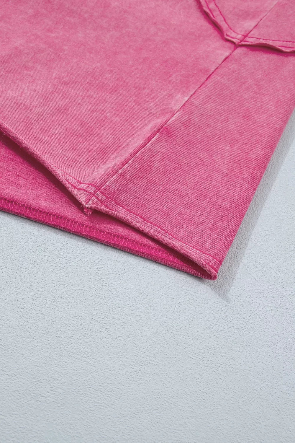 Close-up of pink cap sleeve top showing raw seam details and lace-trimmed hem.