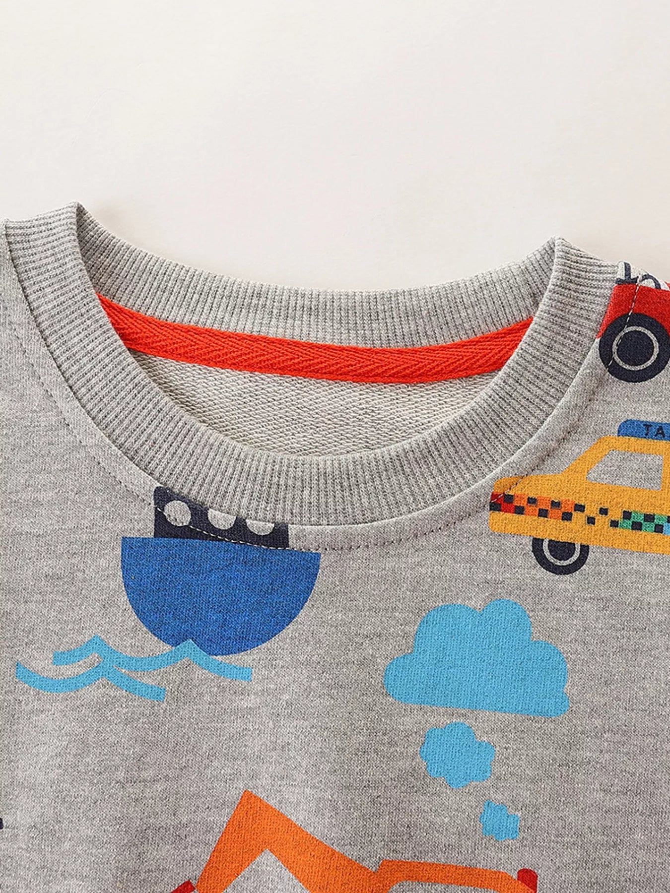 Close up of light gray children's sweatshirt ribbed round neckline with orange inner trim