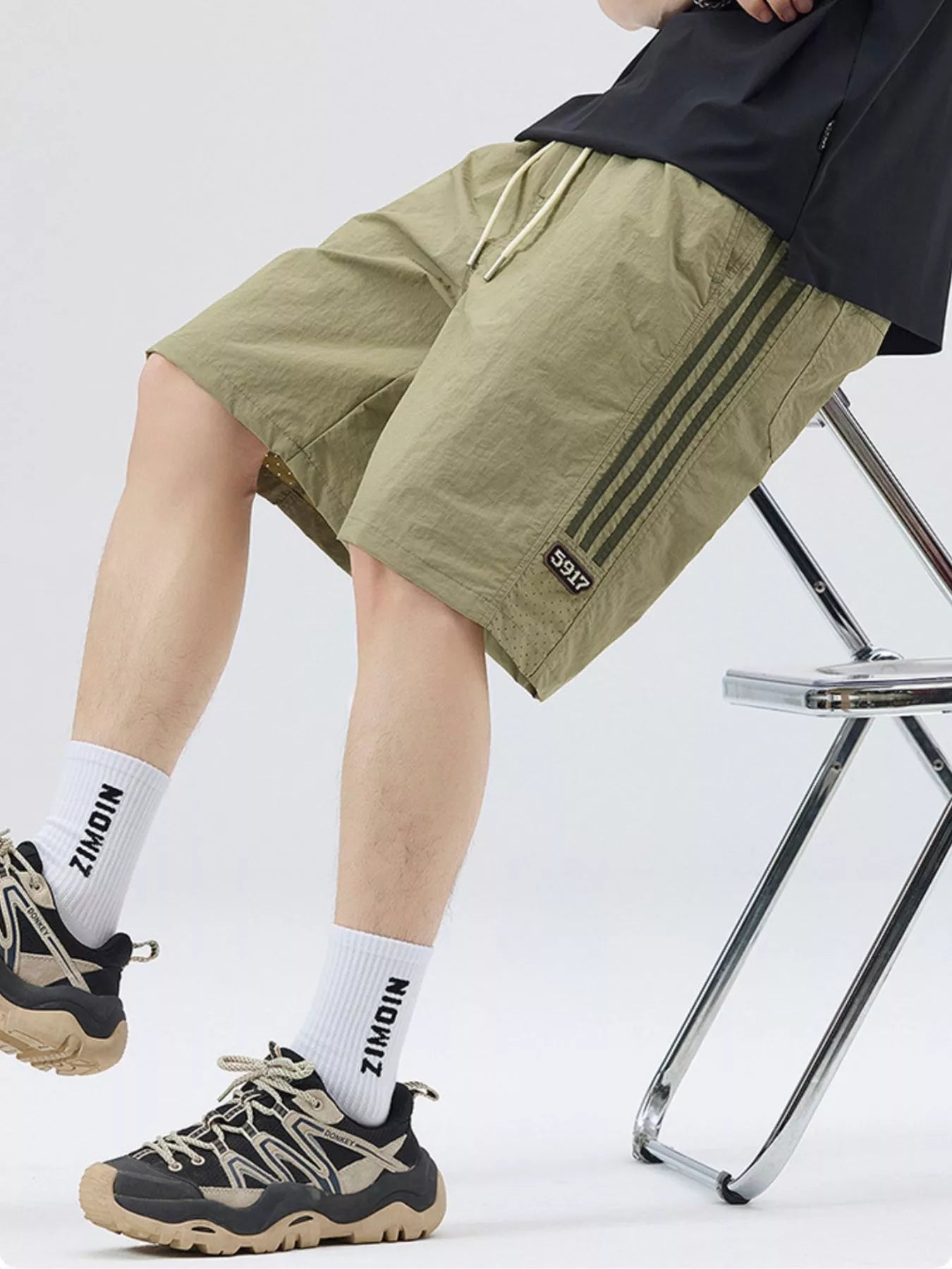 Men's light green loose-fit shorts with stripe detail, a drawstring waist and pockets.