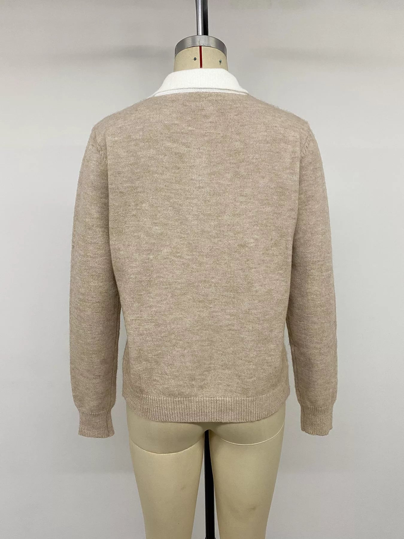 Back view of the solid beige argyle sweater with a white collar on a mannequin