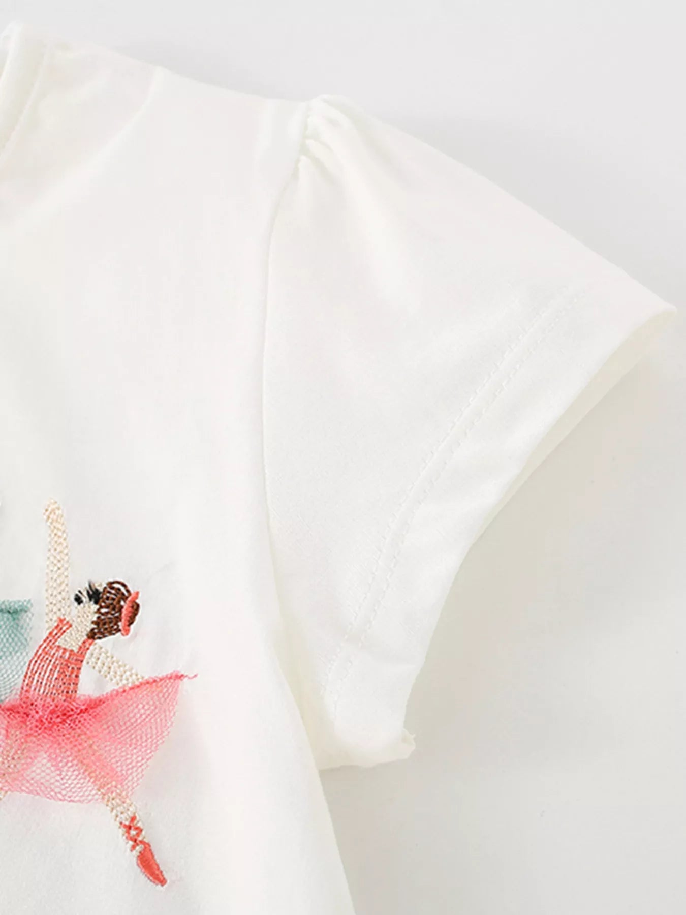 Detail view of a gathered short sleeve and stitching on a children's white ballet dancer tee