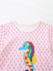 Close-up of the white round neckline and pink patterned fabric on the children's seahorse tee