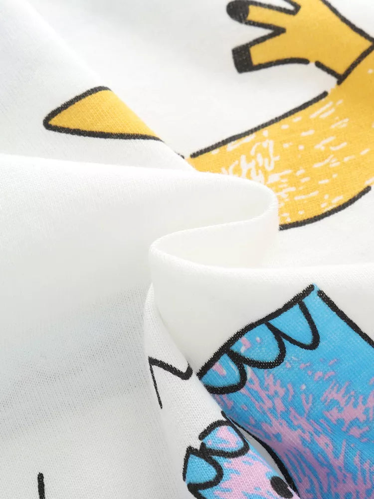 Close-up of folded white fabric with yellow and blue dinosaur prints on the tee