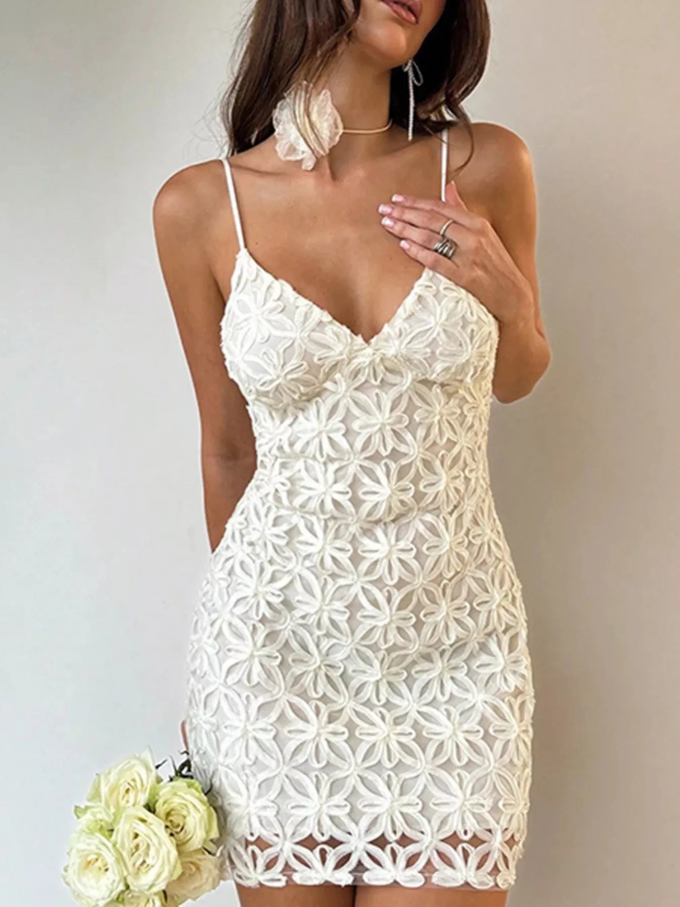 White floral lace bodycon mini dress, front view holding a bouquet of roses