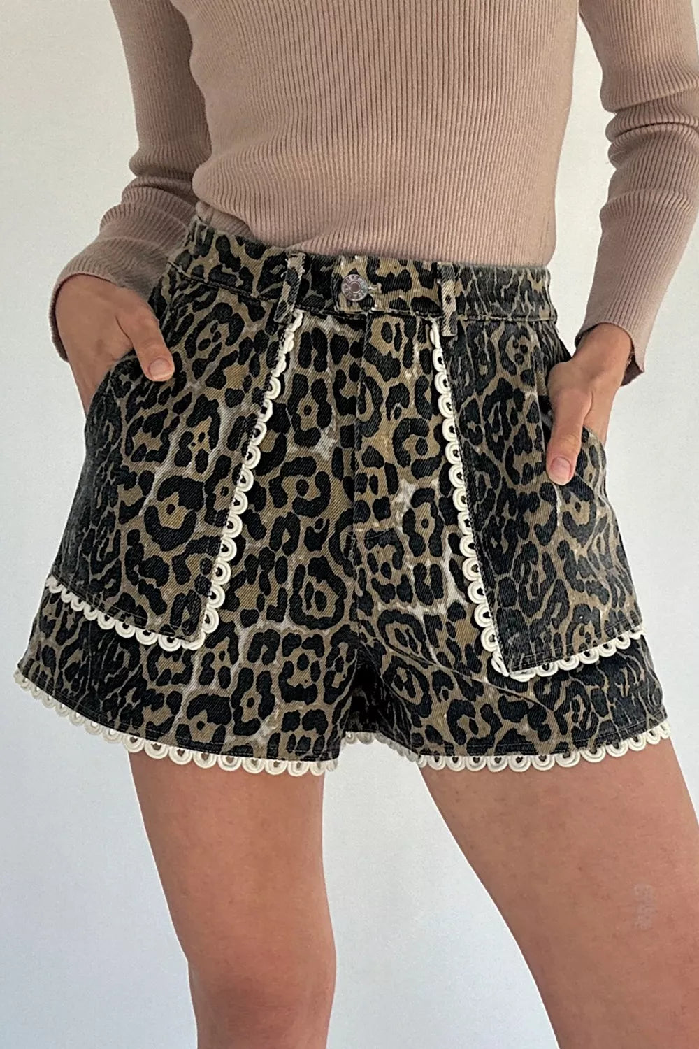 Women's leopard-print denim shorts with lace trim and pockets.