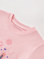 Angled close-up of dusty pink children's tee collar with flower and dotted detail