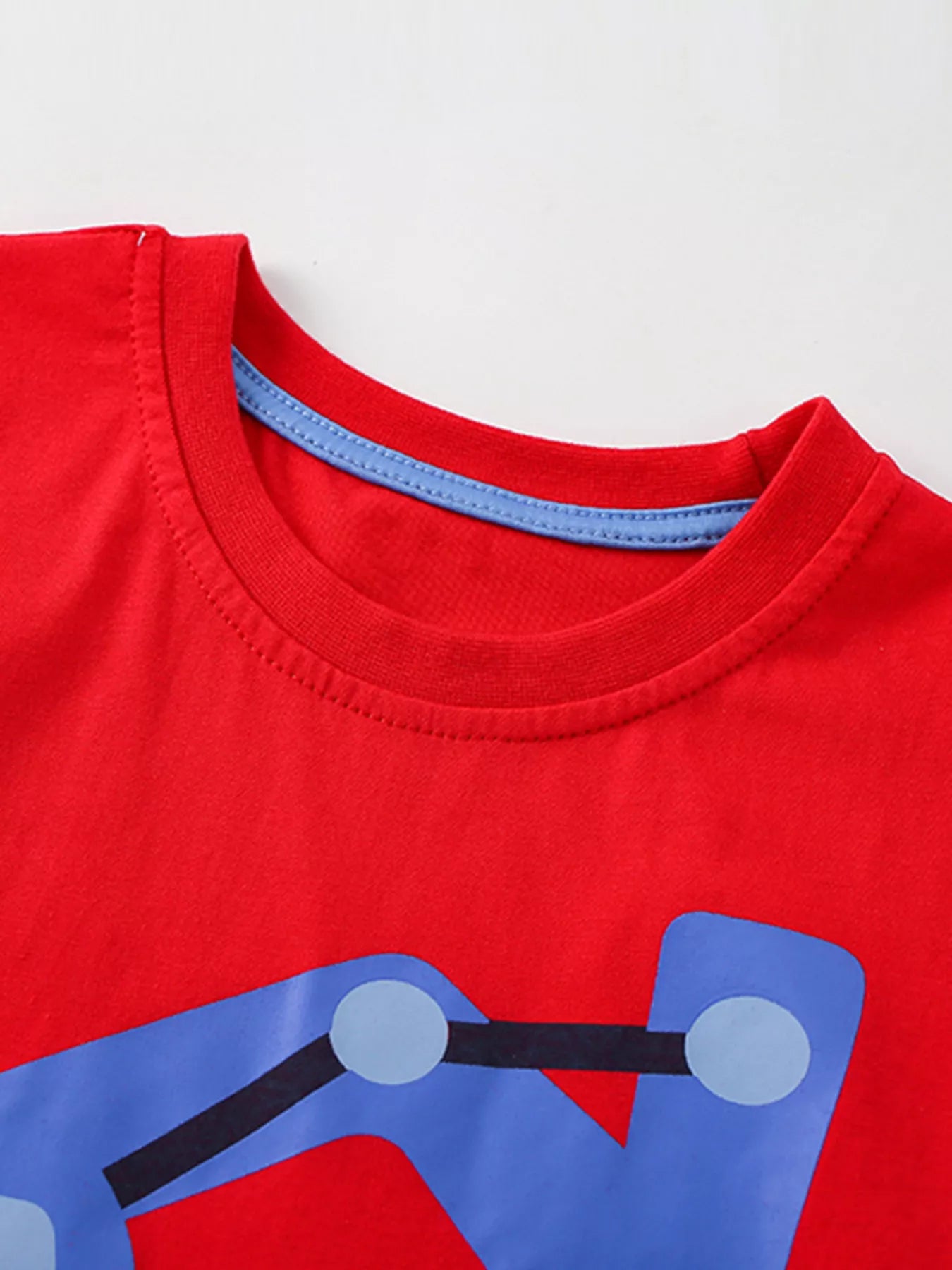 Close up of the red round neckline with blue inner trim above the blue excavator graphic