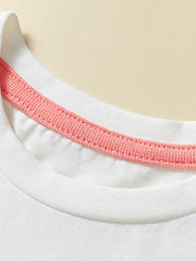 Detail view of the white round neckline with coral inner trim on a children's short sleeve tee
