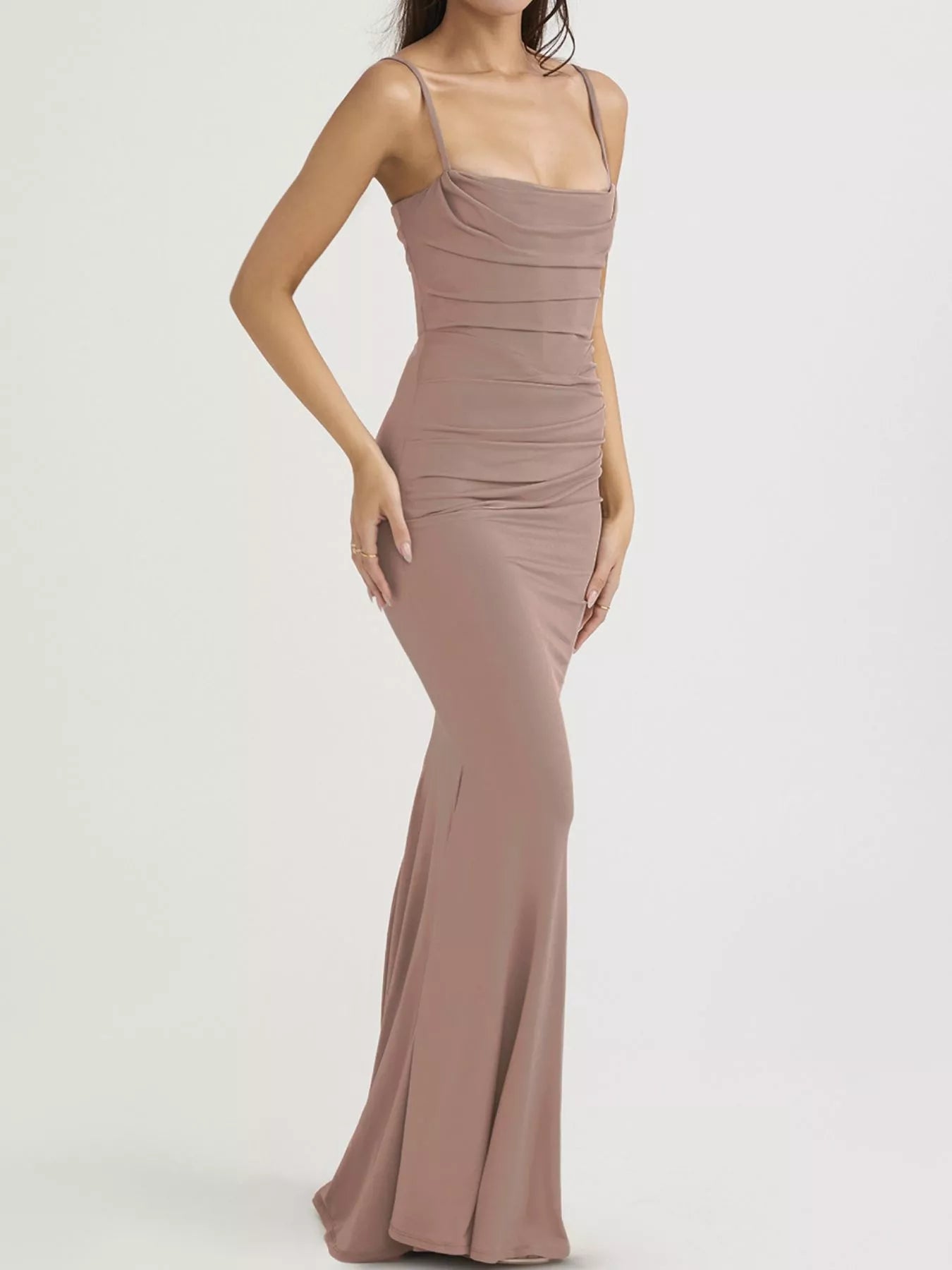 Side view of a dusty pink ruched spaghetti strap bodycon maxi dress in a studio