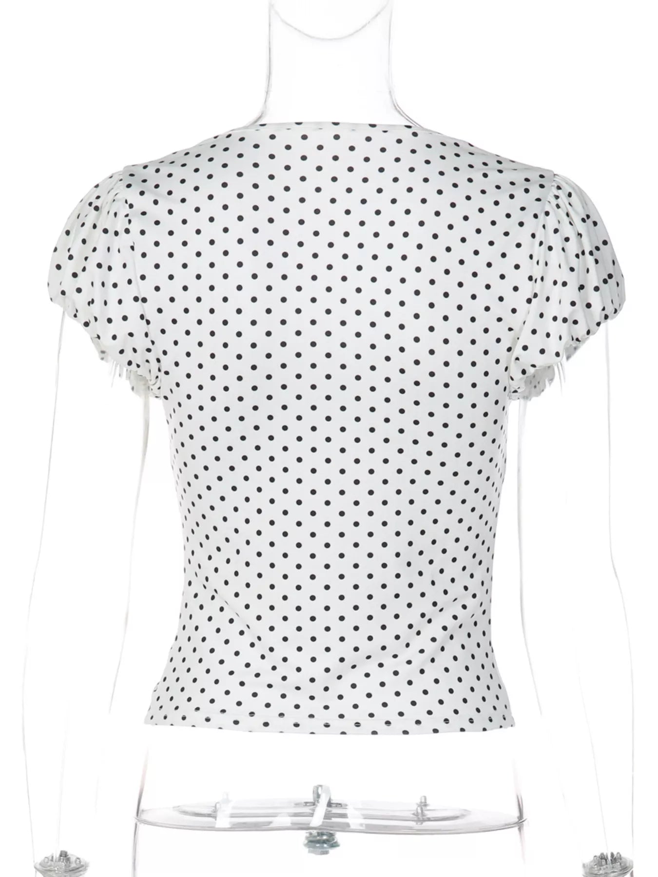 White polka dot top with short ruched sleeves and a V-neckline on a mannequin.