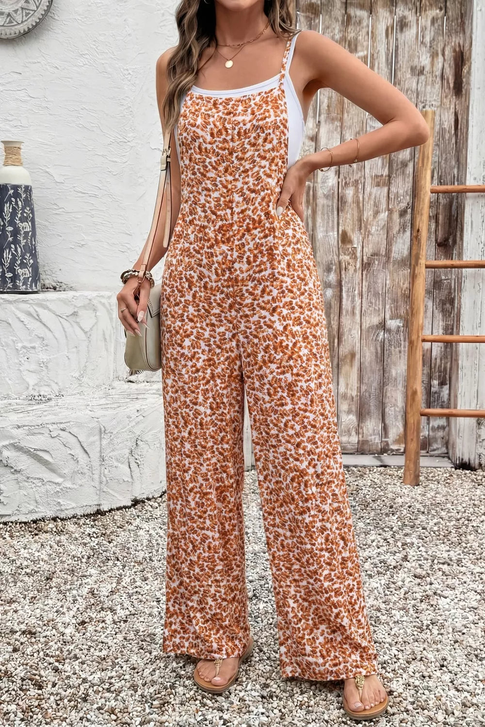 Women's floral-print jumpsuit with spaghetti straps, wide legs, and pockets.