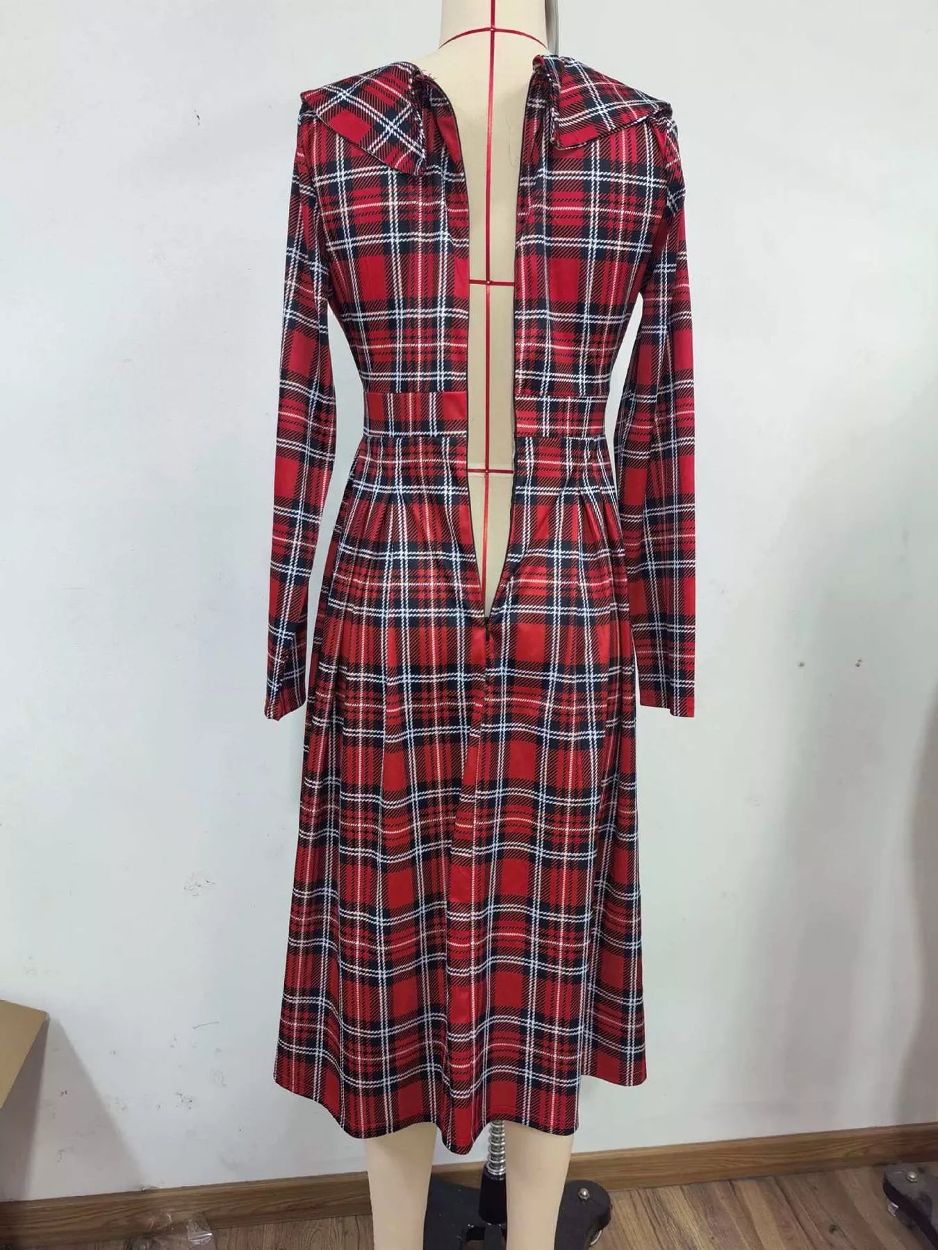 Back view of burgundy plaid long sleeve midi dress on a mannequin, showing center back opening