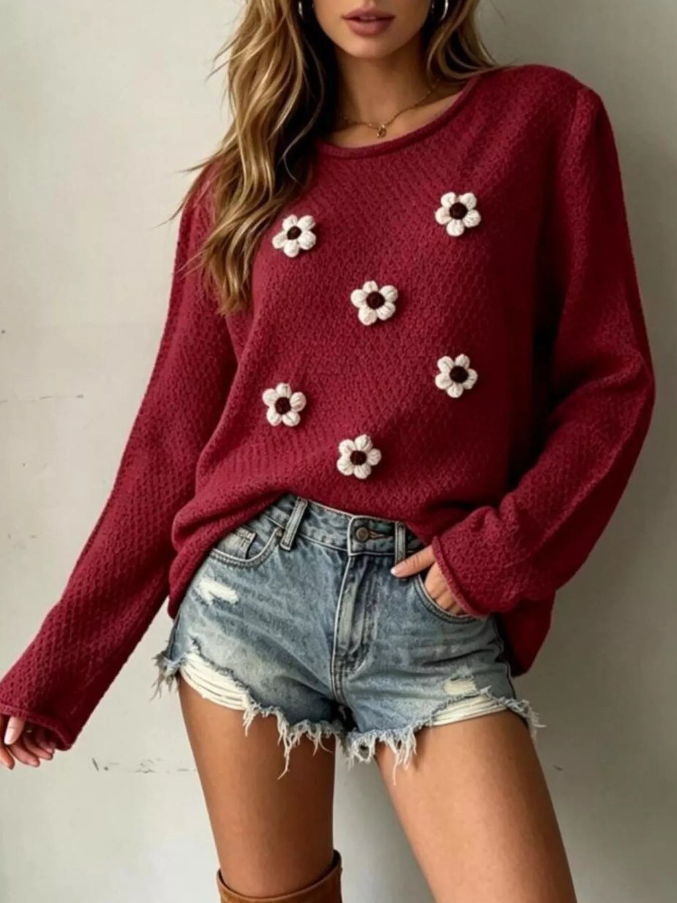 Front view of a burgundy textured knit sweater with white floral appliques and long sleeves