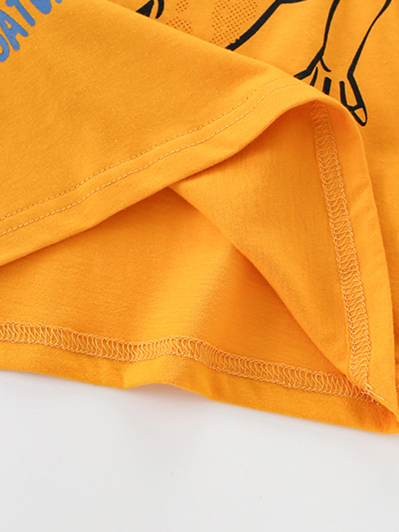 Close-up of the tangerine fabric and stitching at the hem of the children's t-shirt