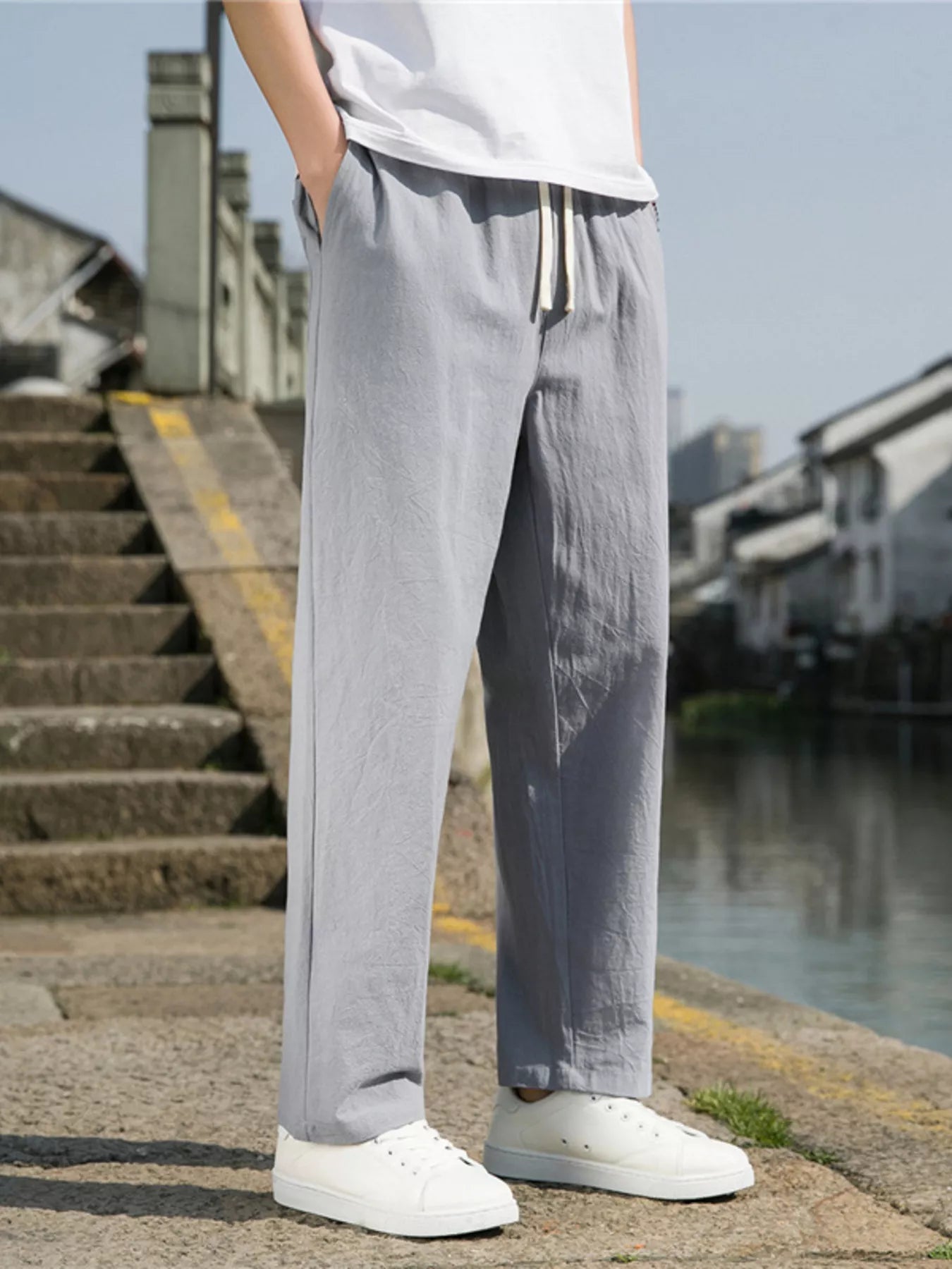 Men's light gray loose-fit casual pants with a drawstring waist and pockets.