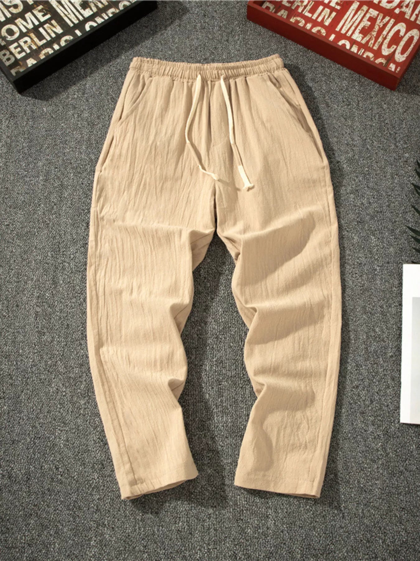 Men's khaki loose-fit pants with a drawstring waist and pockets.