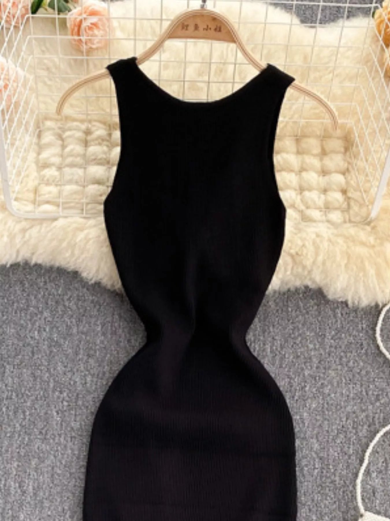 Close front view of black ribbed knit bodice with scoop neckline on hanger