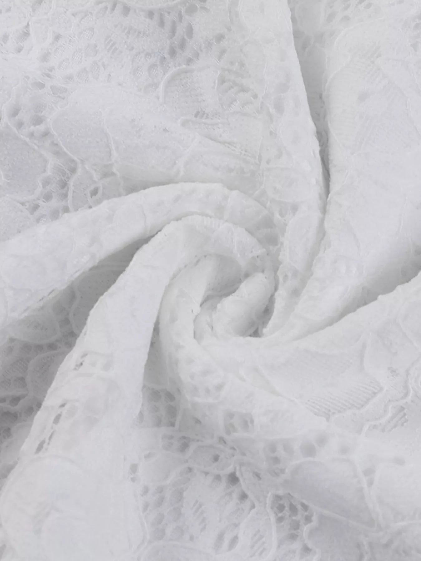 Close up fabric detail of a white lace maxi dress showing the floral lace texture