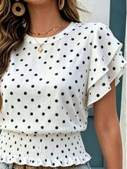 Close-up front view of a white blouse with black polka dots, ruffled sleeves, and a smocked peplum hem