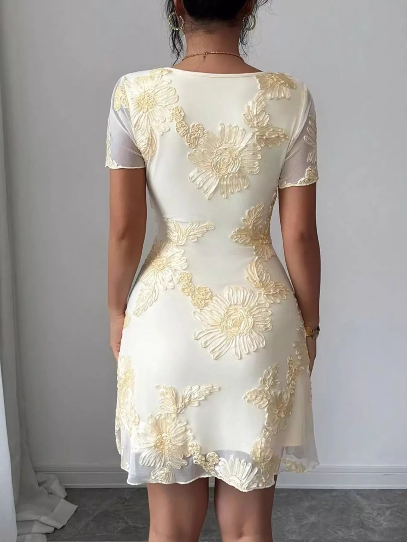 Back view on model of milky white floral mesh short sleeve mini dress with floral applique