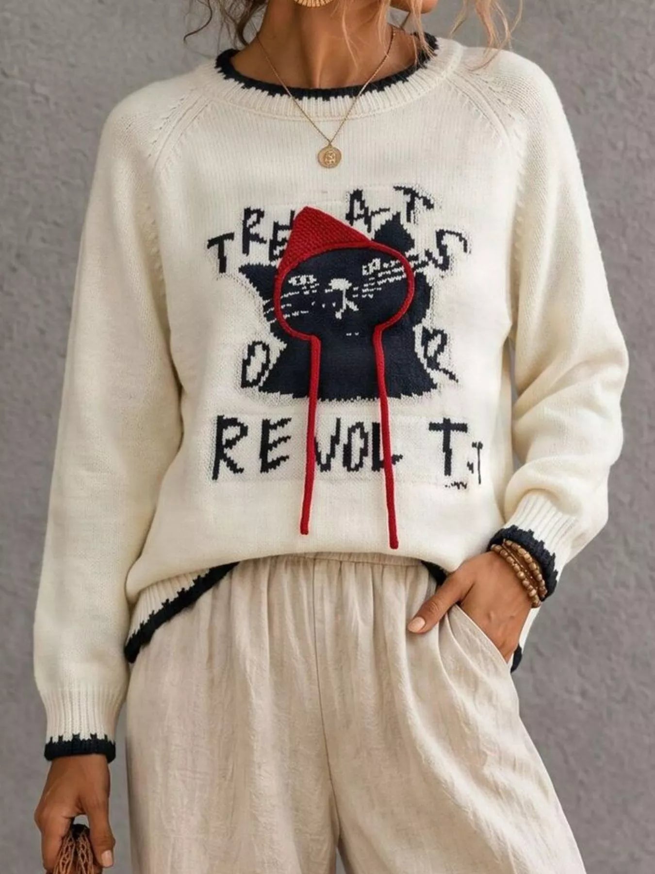 Beige cat sweater with black cat graphic and red hood strings